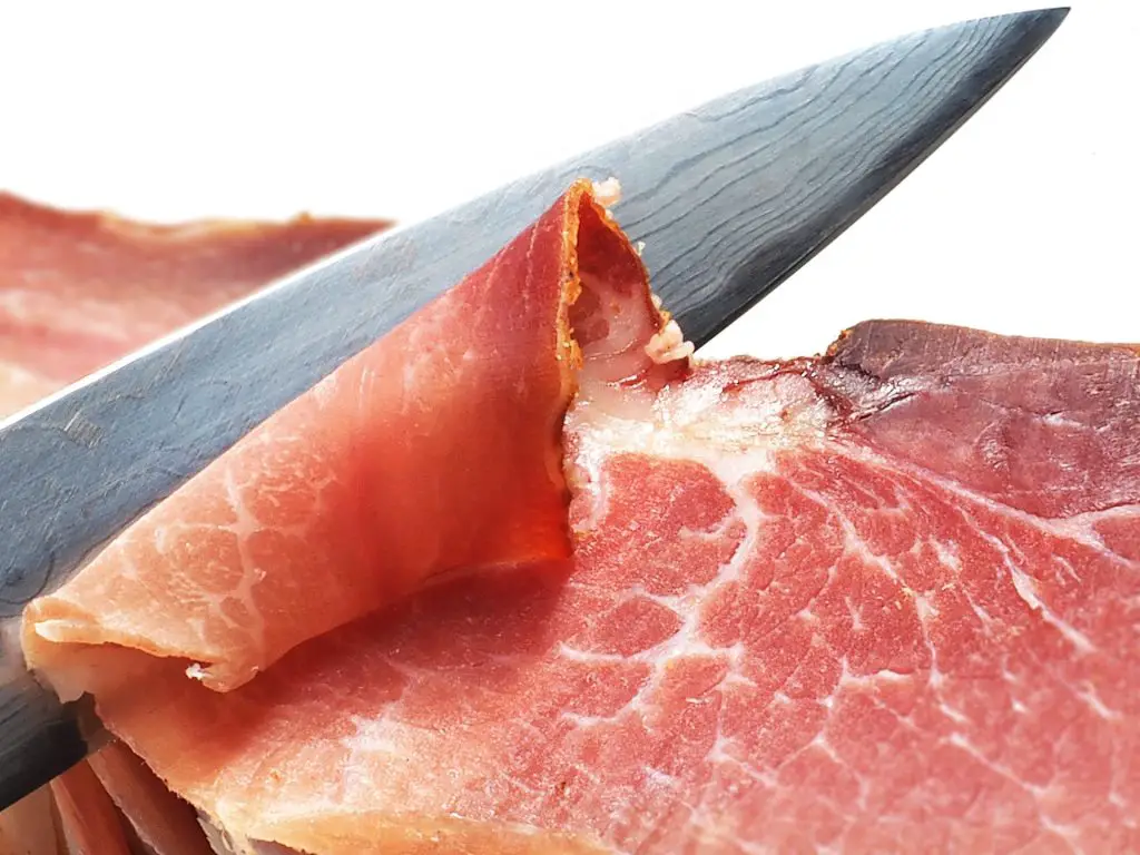 kitchen knife slicing through ham