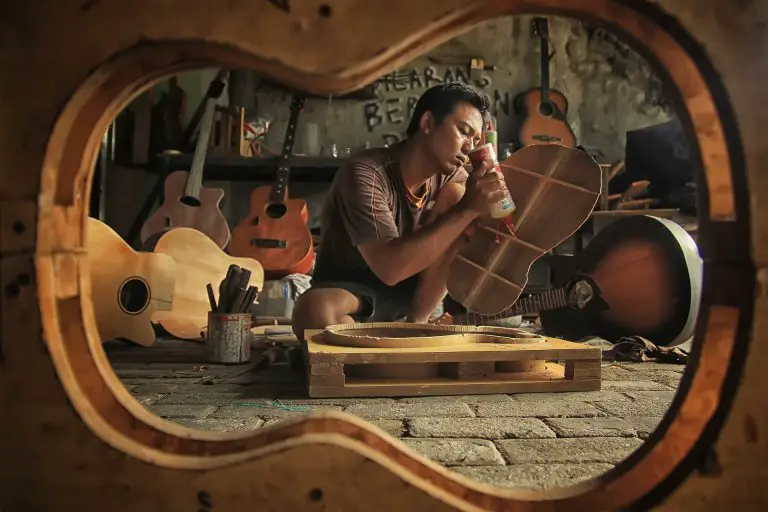 man gluing wooden guitar